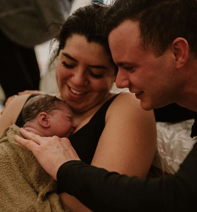 A Haven Birth and Wellness client and her husband hold and admire their newborn baby.
