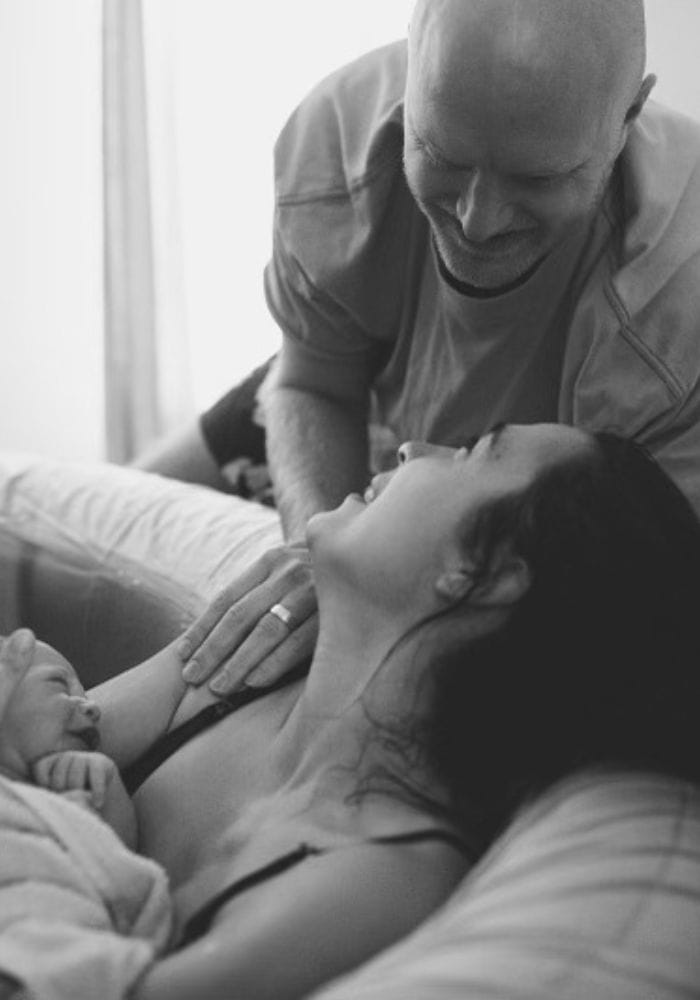 A photo of a Haven Birth and Wellness couple meeting their baby for the first time, smiling at each other.
