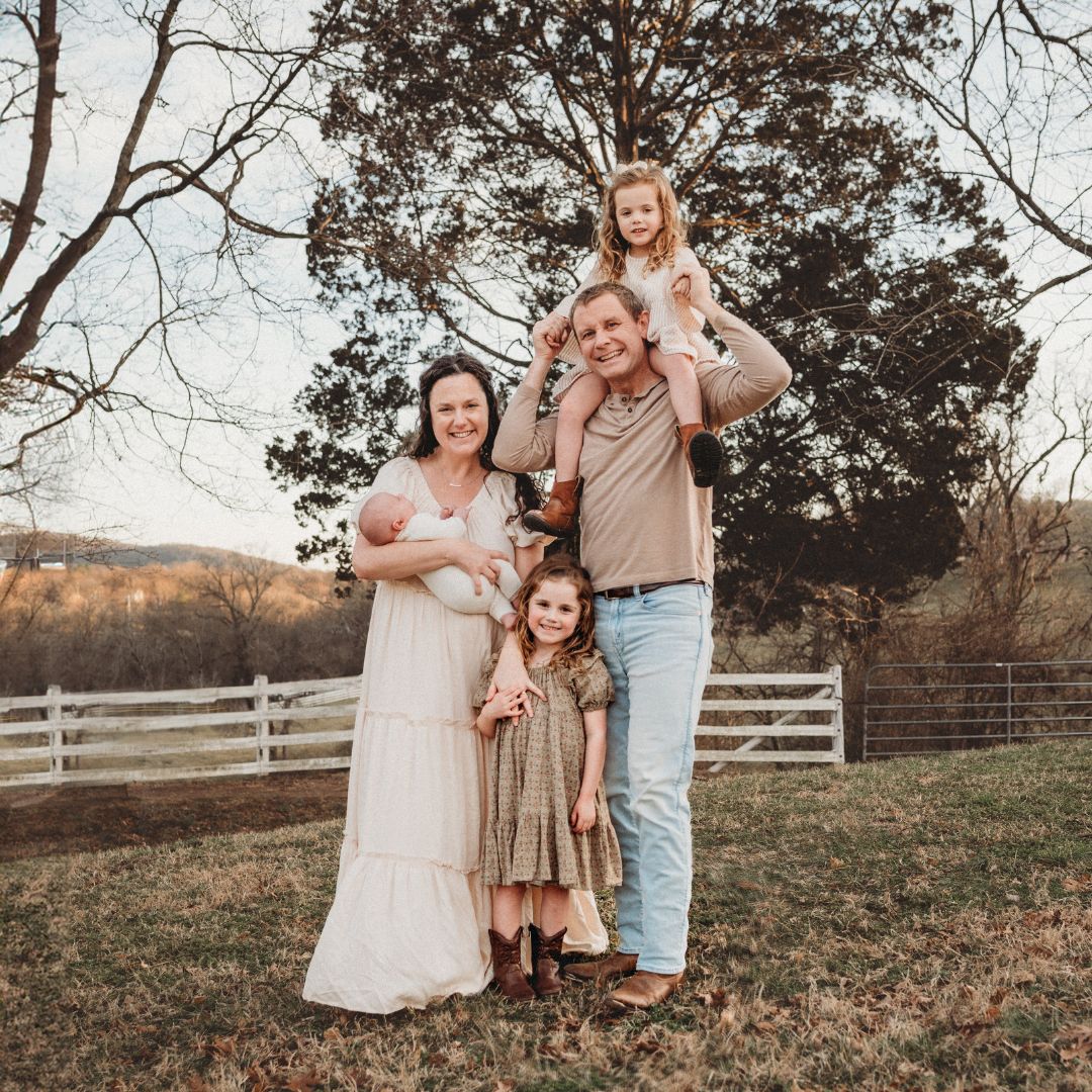 A photo of Carolyn Denning's family in front of a fence, a certified nurse midwife at Haven Birth and Wellness.